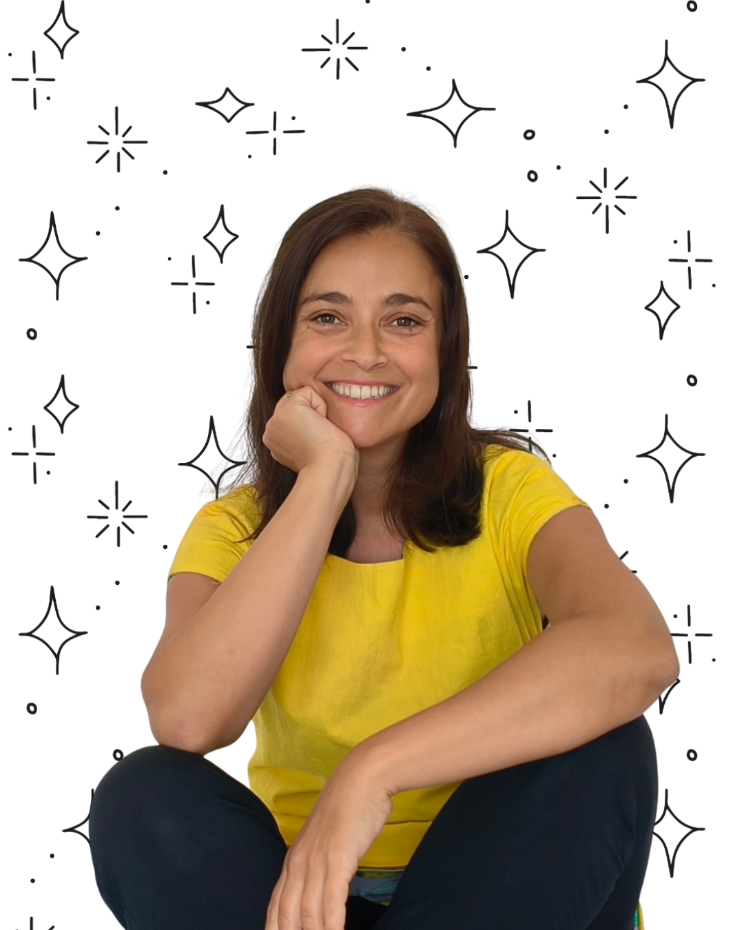 María con una camiseta amarilla sonriendo apoyando su mejilla derecha sobre su mano derecha.